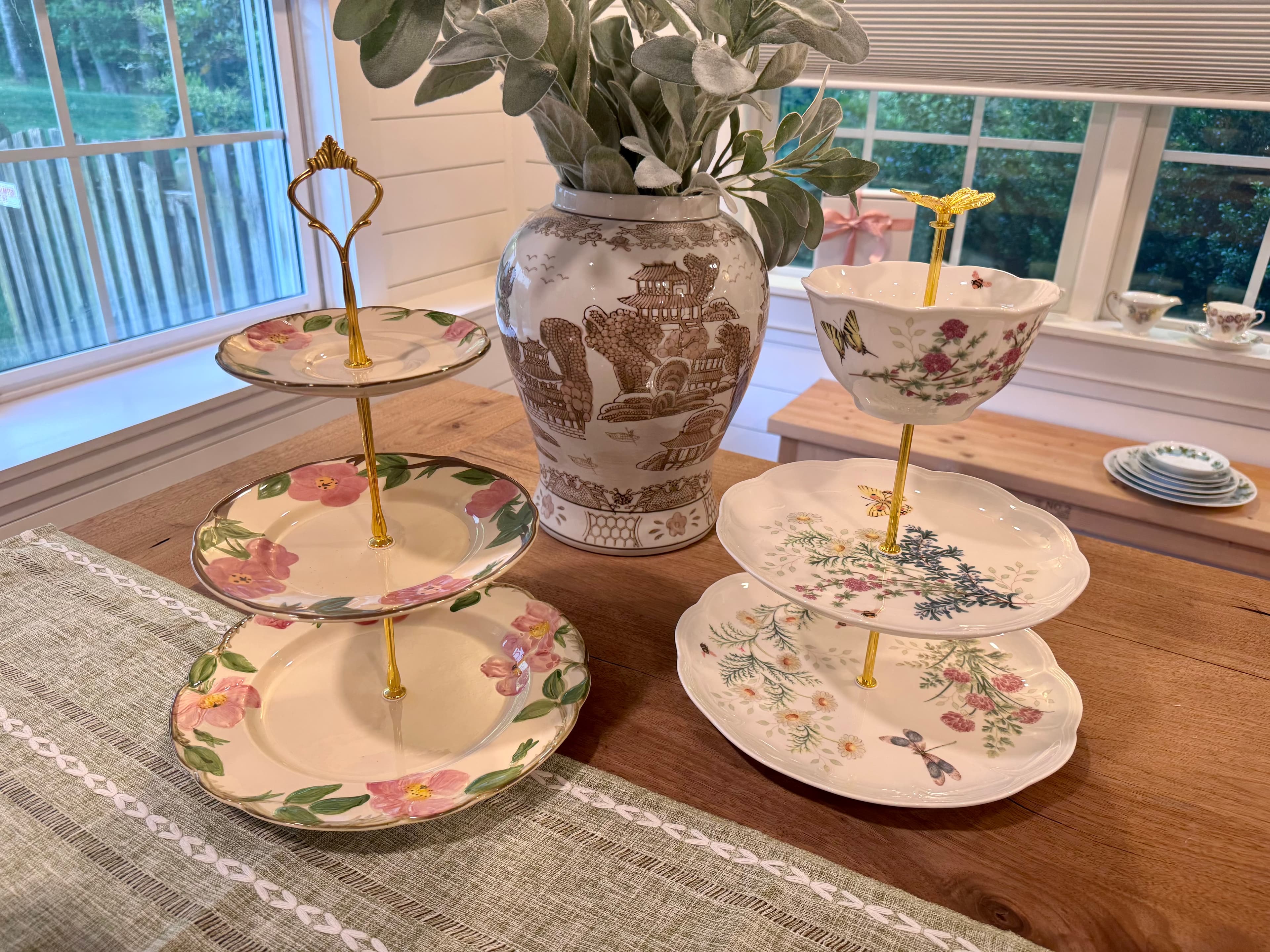Two-tier and three-tier floral china stands beside a vase of greenery